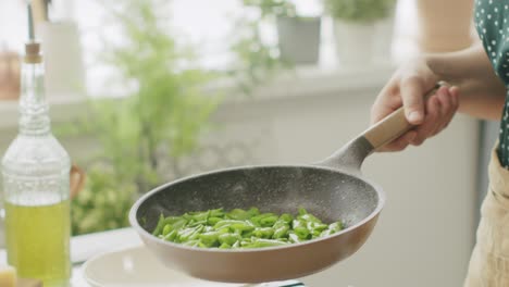 unrecognizable cook frying green beans in pan
