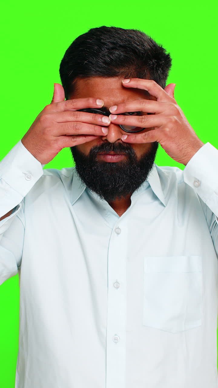 Uomo indiano che si copre un occhio con la mano in un gesto da spia, che mostra intrigo, mistero, segreto, sbirciatina, chroma key