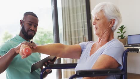 Video-of-happy-african-american-male-physiotherapist-exercising-with-caucasian-senior-woman