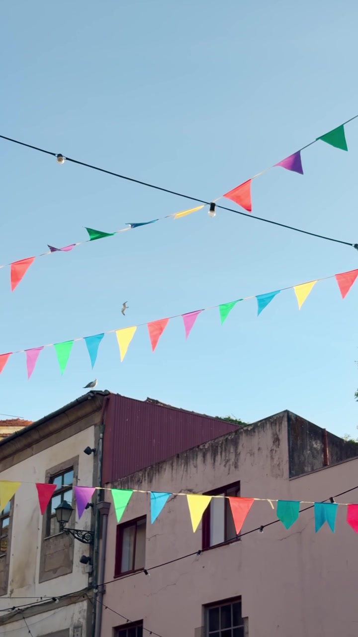 Bandiere appese su una strada urbana in Portogallo, in Europa, filmato in stile verticale POV. Vacanza estiva di un vlogger che viaggia in città e paesi storici. Reel di social media UGC che mostra una celebrazione o un evento