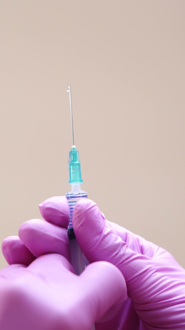 Close-up view on a cosmetologists hands in gloves holding syringe with needle for rejuvenating facial injections. Vertical video