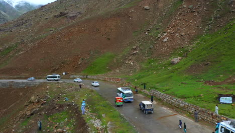 drone shot of vehicles on the babusar pass mountain pass in pakistan in the kaghan valley and children running on the road