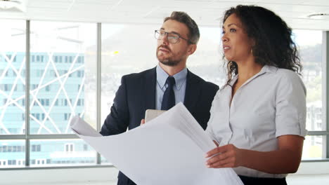 Businesspeople-Meeting-To-Look-At-Plans-In-Empty-Office