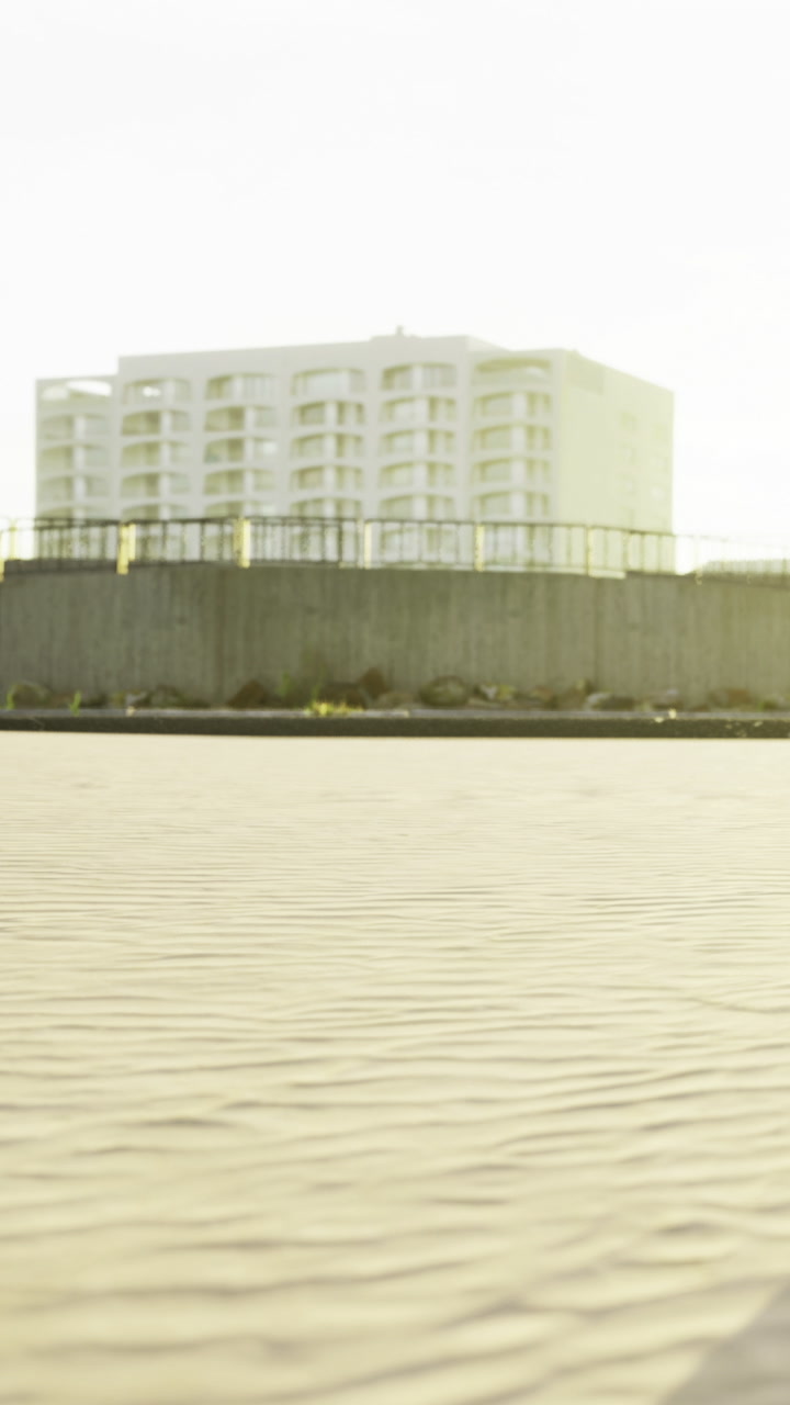 Rippling sand and a modern building basking in the warm afternoon sunlight