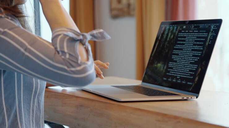 Young woman coding on a laptop at home, symbolizing remote work and tech innovation. Focused environment with warm tones and natural light, modern workspace