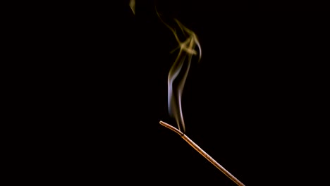 an incense stick burns and smokes.