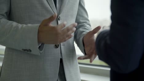 People-gesticulating-while-standing-near-window