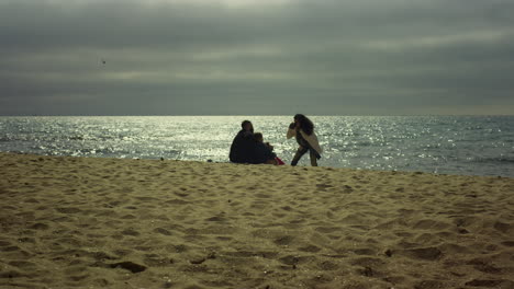 family taking pictures together on sea beach. people posing photo camera on sand