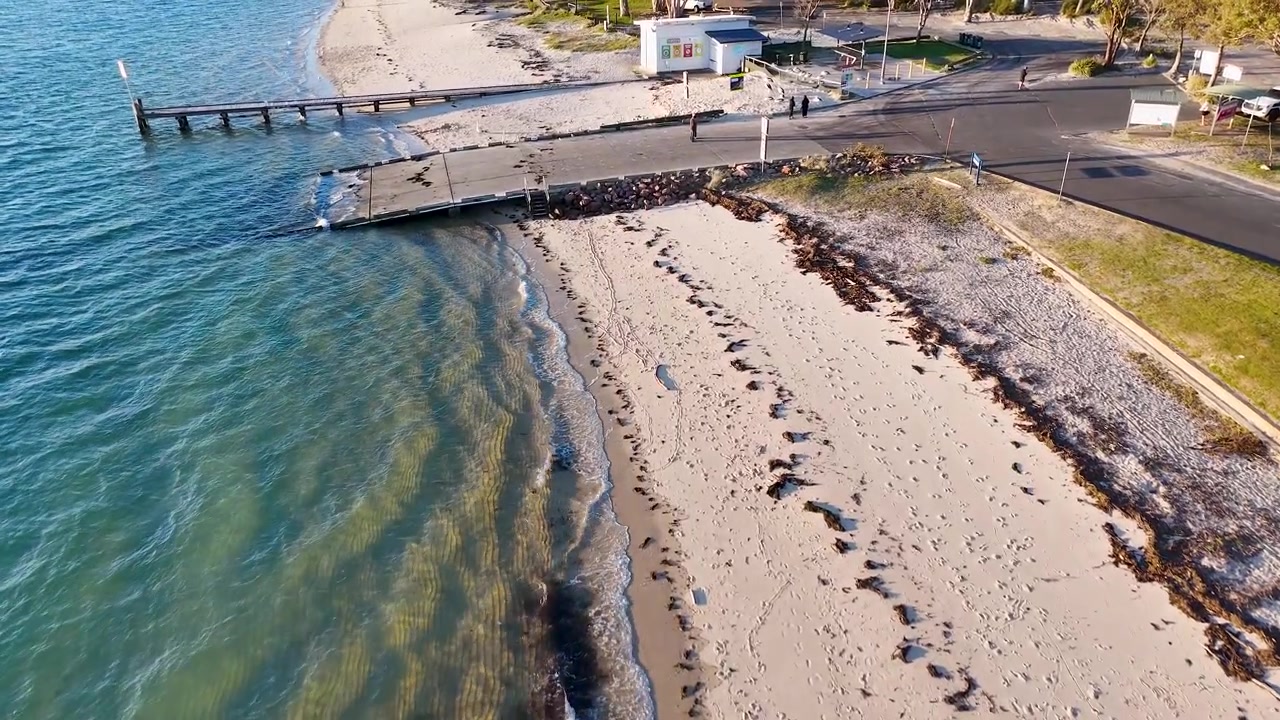 Toma aérea con dron de gran angular de una rampa costera para botes y una orilla arenosa en Nelson Bay, Australia