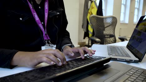 An-individual-is-typing-on-keyboard-within-an-indoor-office-setting,-illustrating-the-notion-of-digital-labour-and-managing-tasks