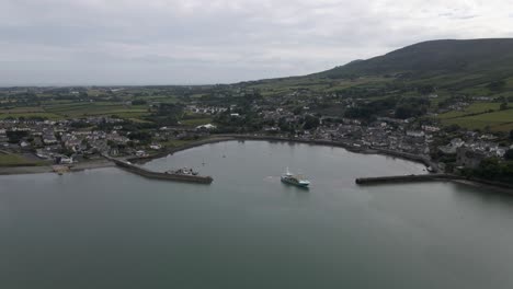 Drone-shot-of-a-fishing-boat-setting-sail-from-a-small-town