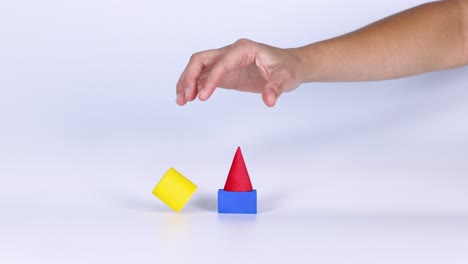 hand stacking colorful geometric shapes on table