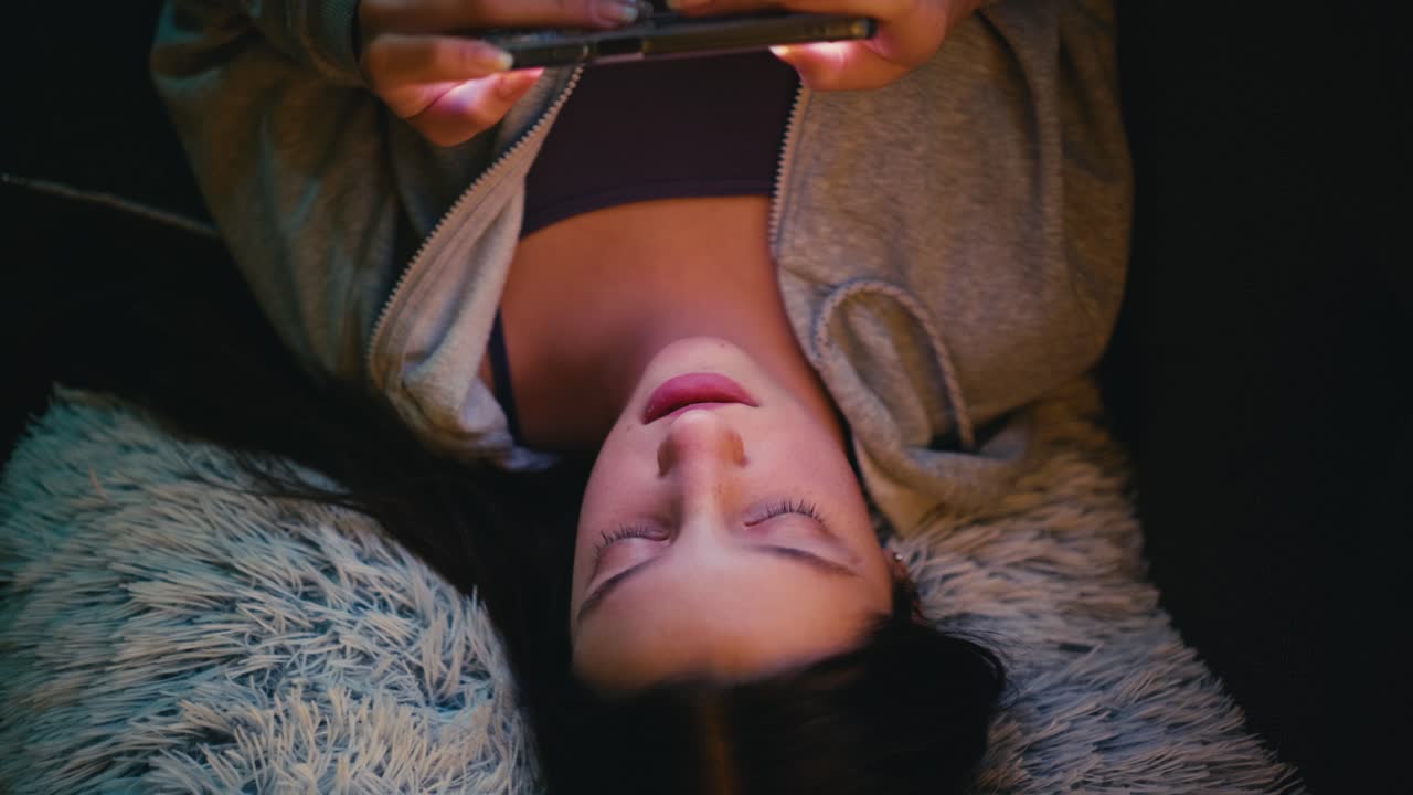 Teenage girl relaxing on a cozy couch, intently using her smartphone. Warm natural lighting enhances the tranquil and casual atmosphere.