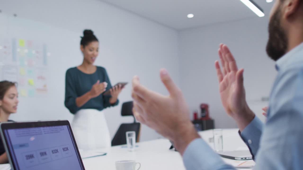 Diverse male and female office colleagues clapping after the presentation in meeting room at office