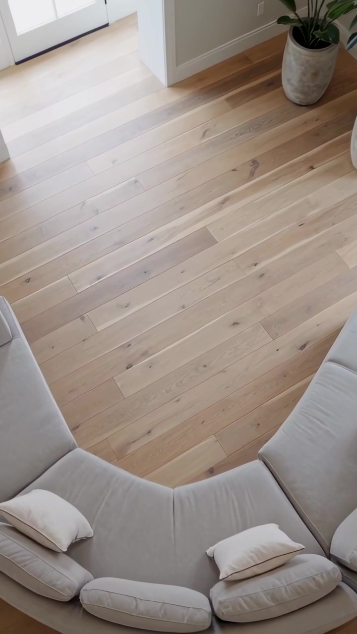 Vertical video: Lowering camera revealing curved sofa near front door, showcasing pillows and floor