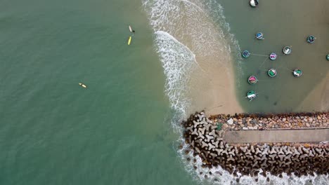 Topdown-view-of-traditional-fishing-boats-moored-near-Stone-jetty,-Mui-ne,-Vietnam