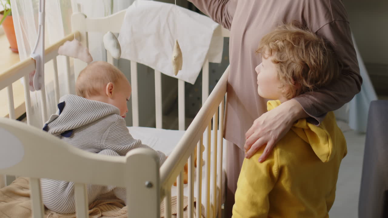 Mother and Little Son Talking by Baby Crib