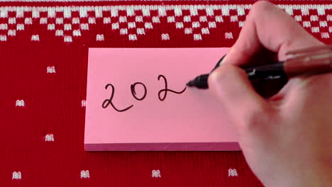 writing year twenty twenty on pink post it note against red design background