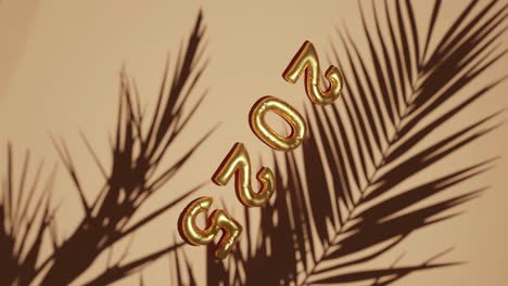 golden ballon 2025 on silhouetted palms brown background vertical