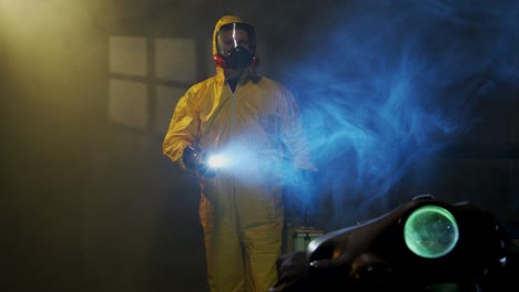 hombre vestido con traje de materiales peligrosos explora una habitación llena de humo