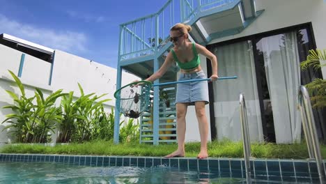 woman cleaning pool in tropical resort
