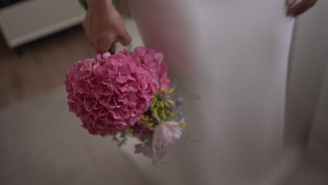 bride’s hand delicately holds a vibrant pink hydrangea bouquet before ceremony