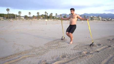 entrenamiento metabólico en la playa con un hombre musculoso que realiza la espalda y una variante de goma con pesas rusas