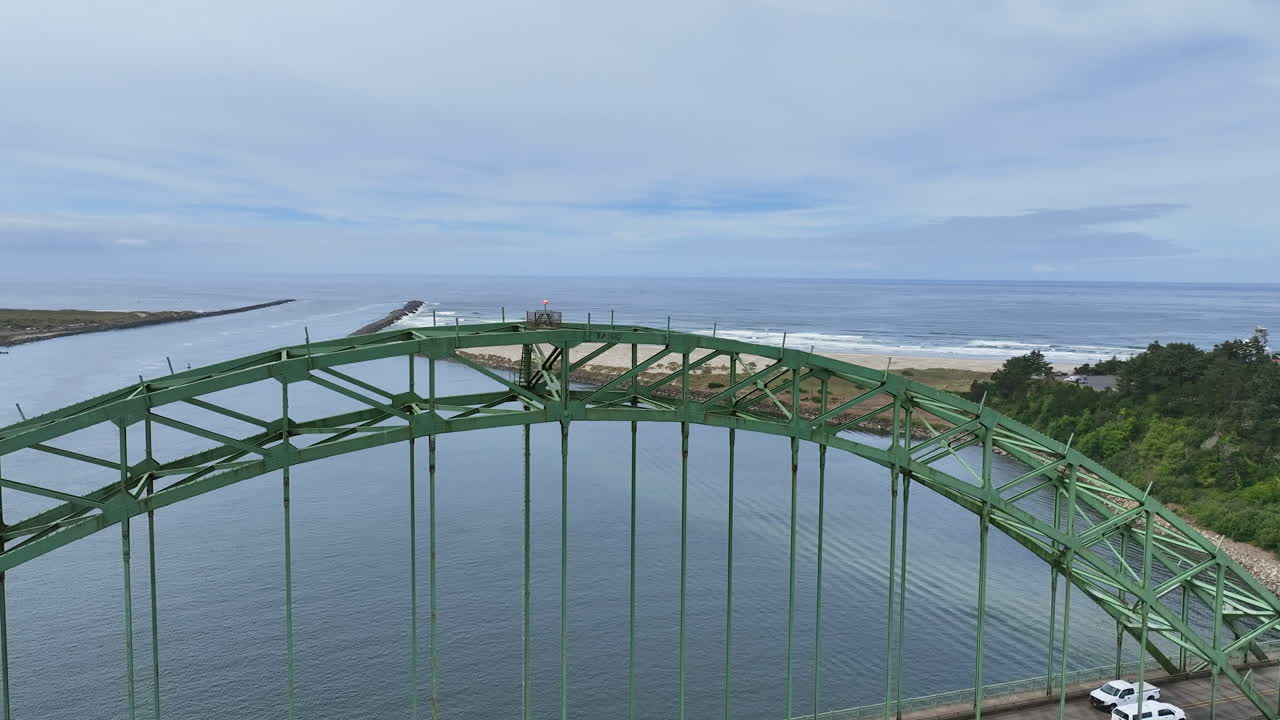 Drone rising over the Yaquina Bay Bridge, toward the beach in cloudy Newport