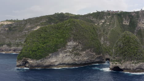 pivote lento alrededor de la península en la playa de kelingking con acantilados escarpados en un día nublado, nusa penida, indonesia