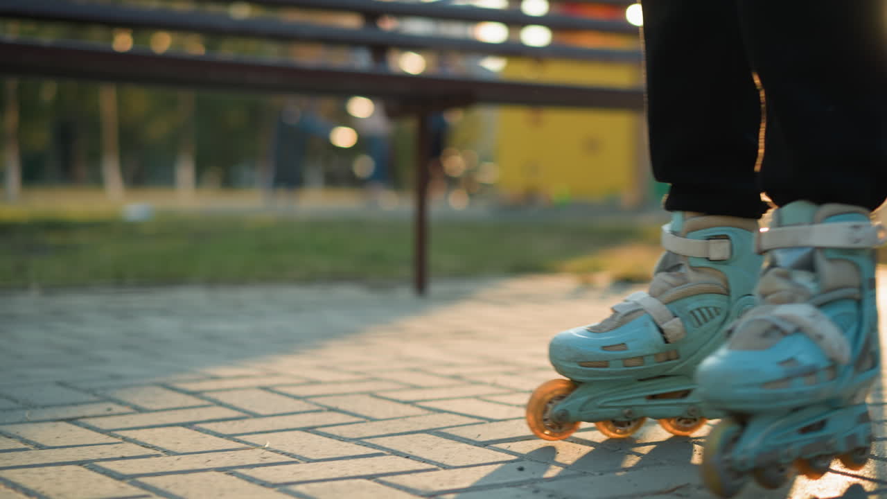 A close-up shot of a person s feet wearing rollerblades, gliding smoothly along a paved path in a park. The background is blurred, focusing attention on the rollerblades and the motion of skating