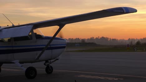 avión cessna con hélice giratoria preparándose para despegar en el aeropuerto durante la puesta de sol