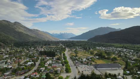 dolly in flying above lago puelo village leading to a pine tree forest with lake and andean mountains in background at sunset, chubut, patagonia argentina