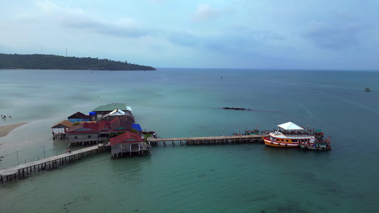 cambodia Koh Rong island, capturing the essence of tropical paradise with its lush palm trees, vibrant turquoise waters, and traditional stilt houses. Amazing aerial view flight descending drone