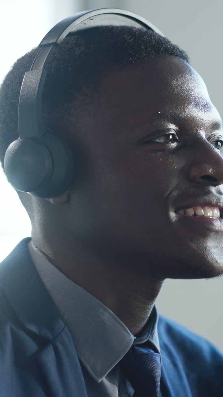 Profesjonell afroamerikansk mann med hodesett smiler og snakker.