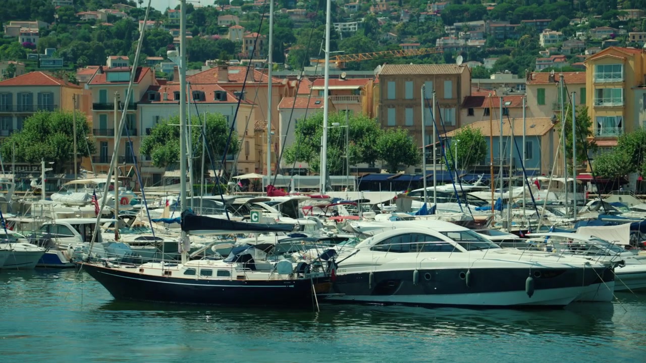 Yacht di lusso e barche a vela che riempiono l'affollato porto turistico di Cannes, con edifici colorati e colline sullo sfondo, Antibes, Francia.