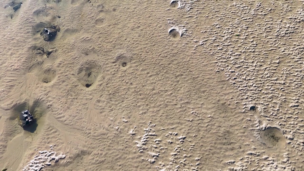 Ripresa aerea con drone di intricati motivi di sabbia e increspature su una spiaggia in Australia