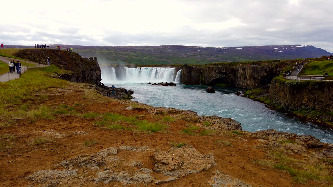 hermosa cascada godafoss islandesa de 12 metros y 39 pies de altura en forma de herradura en el río skjálfandafljót en el norte de islandia, amplia estática desde el frente con turistas caminando 4k prorezhq
