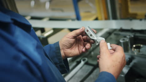 Over-the-shoulder-view-of-a-worker-inspecting-the-quality-of-a-finished-product-after-it-comes-from-an-automated-production-line-in-the-factory