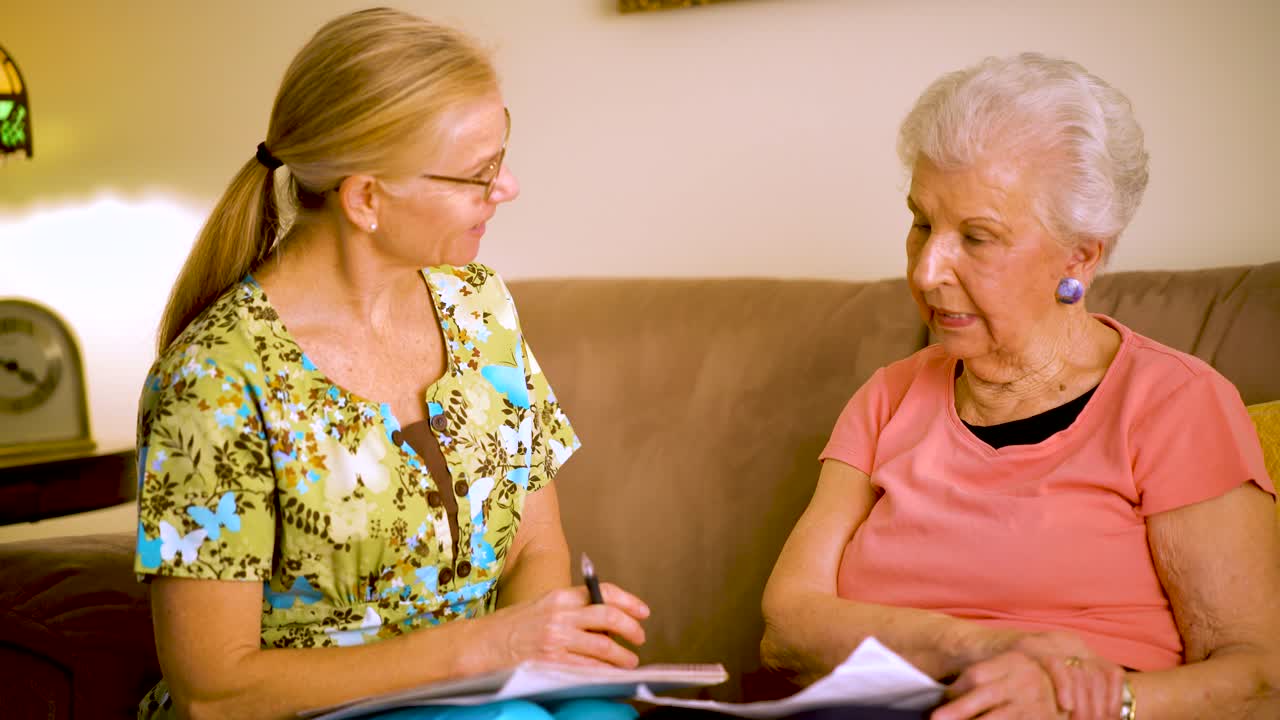 Closeup of elderly woman and home healthcare nurse going over paperwork