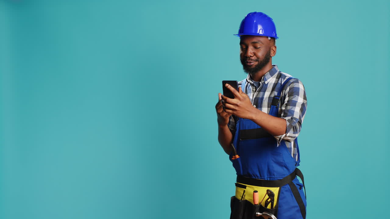 Cheerful builder talking on video call meeting in studio