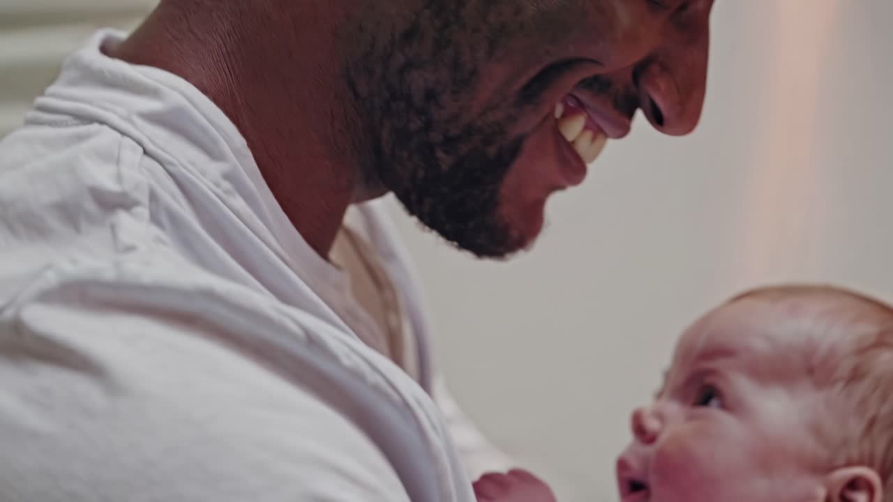 Close-up video still of a joyful father and baby, capturing a tender moment