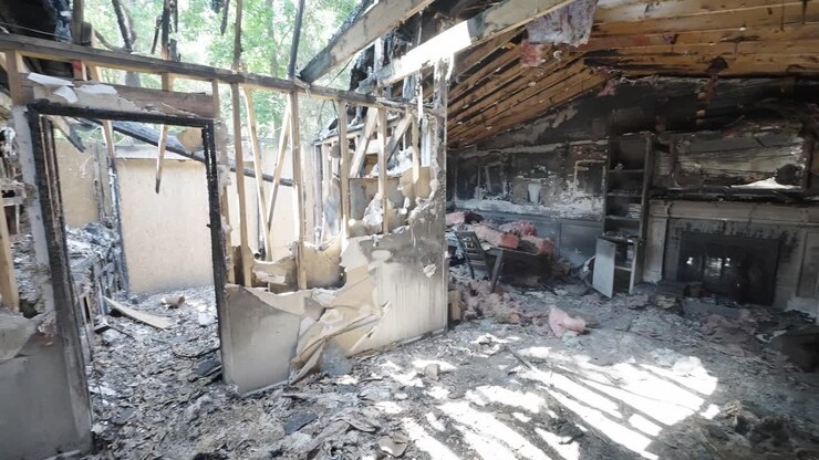 Danni da un incendio domestico che mostrano un soggiorno e una sala da pranzo fatiscenti, con ripresa panoramica da destra a sinistra