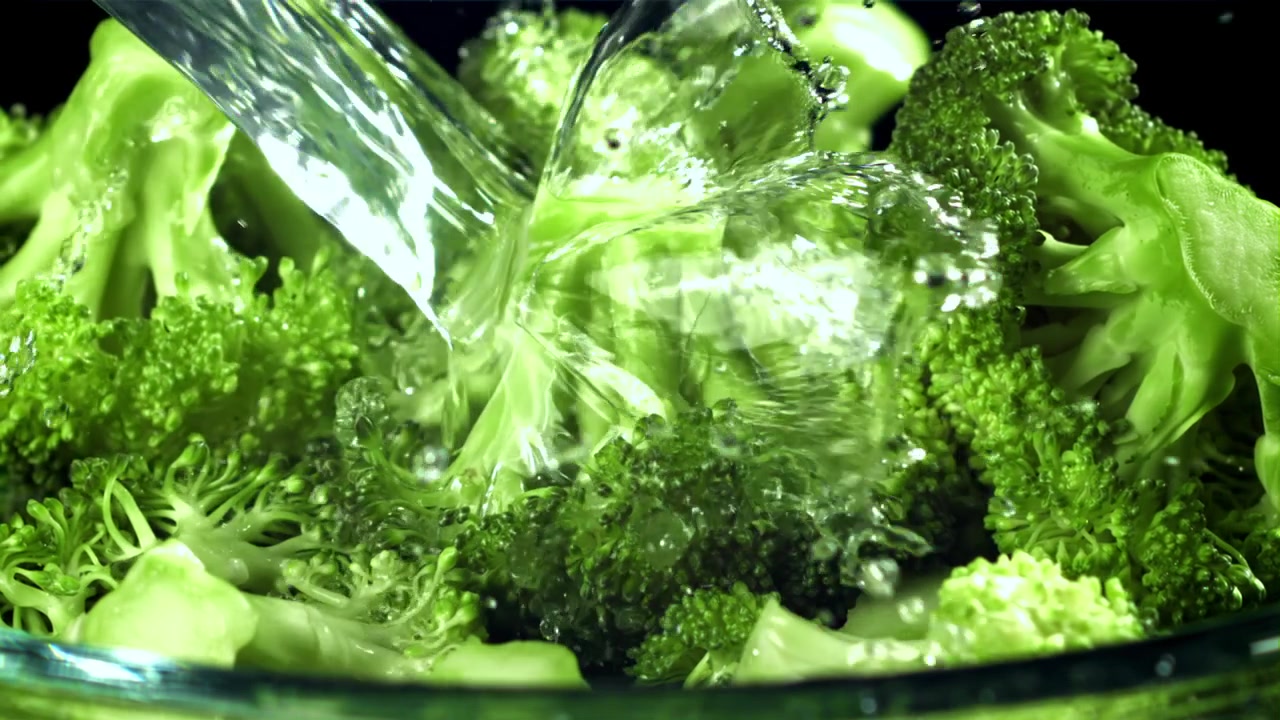 Acqua che si versa su broccoli freschi e verdi al rallentatore