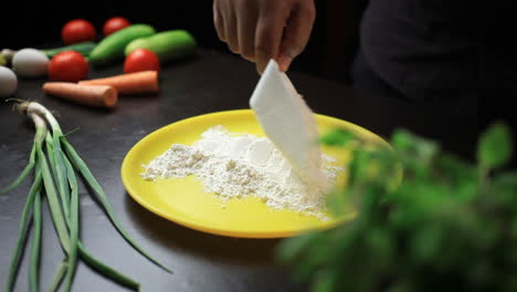 spreading refined flour on a yellow coloured plate with scoop