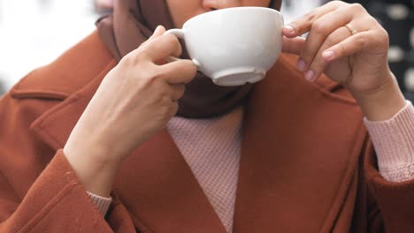 woman in hijab enjoying a warm drink outdoors