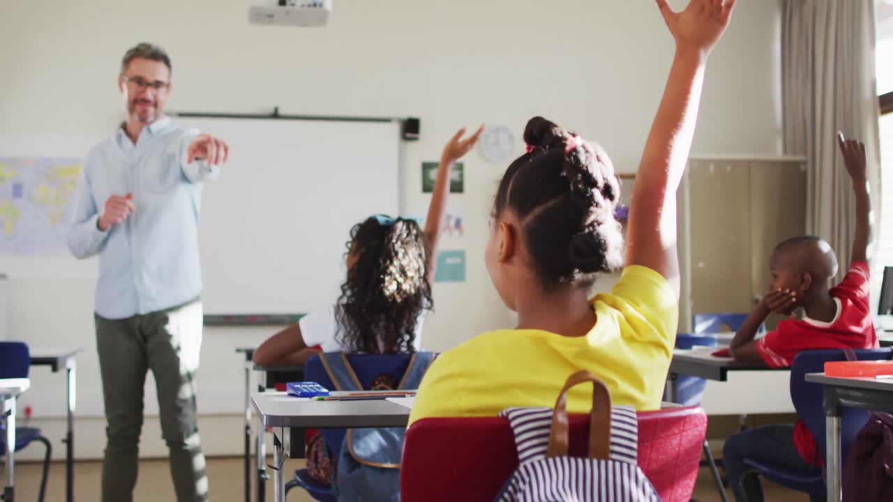 feliz profesor masculino caucásico en el aula con los niños levantando las manos durante la lección