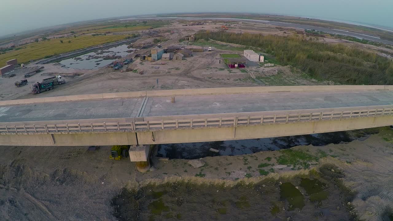 vista aérea del puente construido sobre el río con camiones pesados y maquinaria, granjas en el río