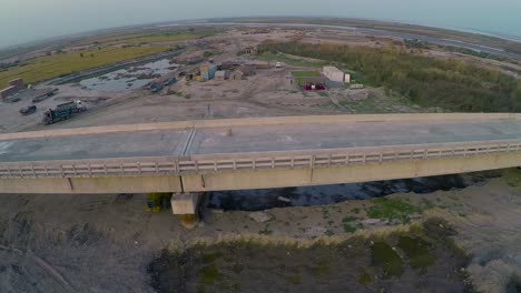 vista aérea del puente construido sobre el río con camiones pesados y maquinaria, granjas en el río