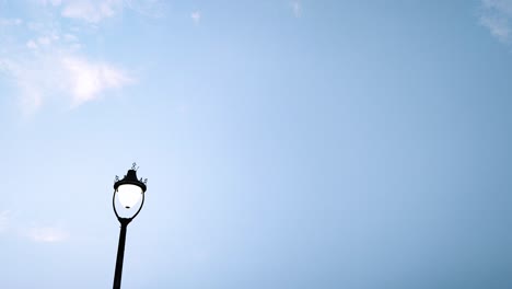 real-time upward to downward tilt shot of vintage street lamp agains clear blue sky. ideal for transitions, city scenes or background use in films and ads