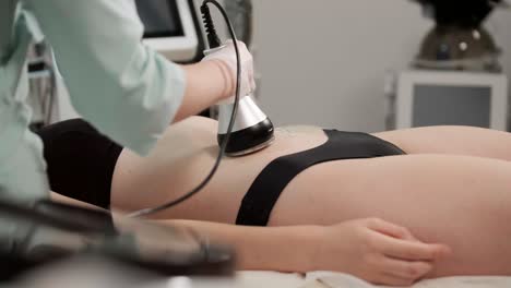 cavitation body contouring treatment. woman getting anti-cellulite and anti-fat therapy in beauty salon